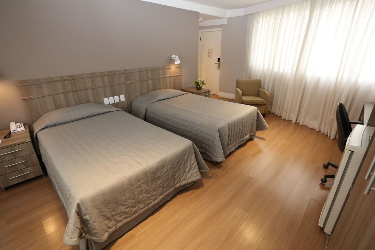 Um quarto de hotel com duas camas e uma cadeira